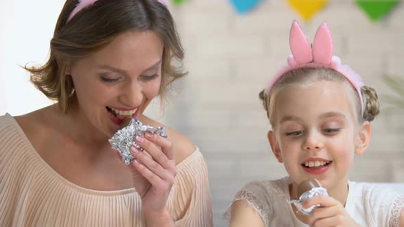 Cute Daughter and Mother Eating Chocolate Eggs Enjoying Pastime Together, Family