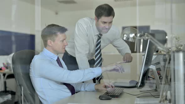 Mature Businessman Using Office Computer and Celebrating Success with Colleague