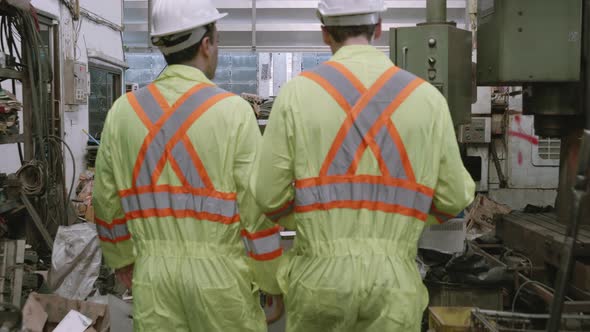 Team engineer in hard hat walking and talking with professional in industrial factory.