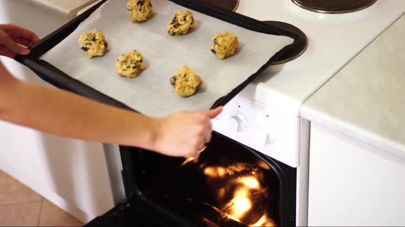 Girl Puts in the Oven a Baking Sheet with American Cookies with Chocolate Chips