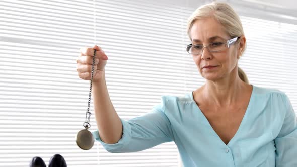 Hypnotist holding a pendulum on her patient