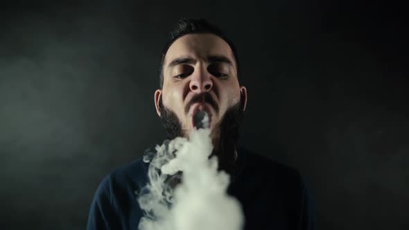 Close-up Portrait of Bearded Man Vaping Many Small Steam Circles To Camera