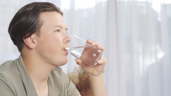 Young man drinking water from a glass.