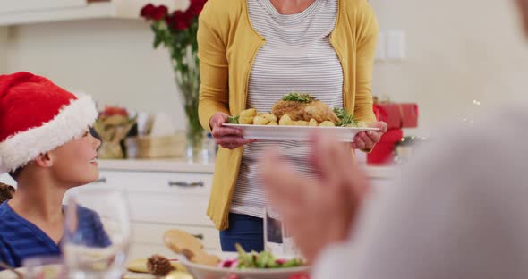 Caucasian woman in santa hat serving food to whole family