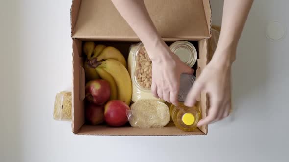 Woman Takes Out Food Products From Donation Box Top View