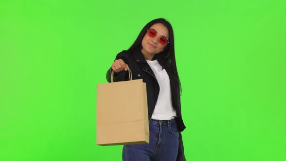 Happy Beautiful Stylish Woman Holding Out Shopping Bag To the Camera
