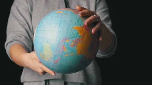 Girl's Hands Twist the Geographic Globe Around Its Axis