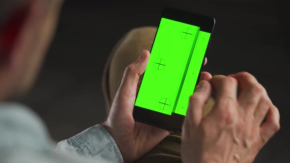 Man Using Smartphone with Green Mockup Screen in Vertical Mode