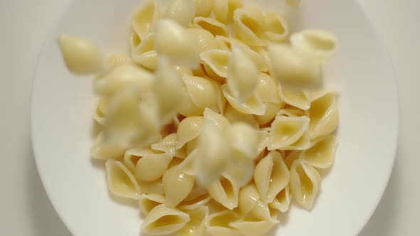 SLOW MOTION: Rigate Pasta Falling Into A White Plate - Top View