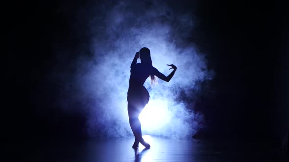 Woman Dancing in Studio, Silhouette. Dark Background, Blue Backlight