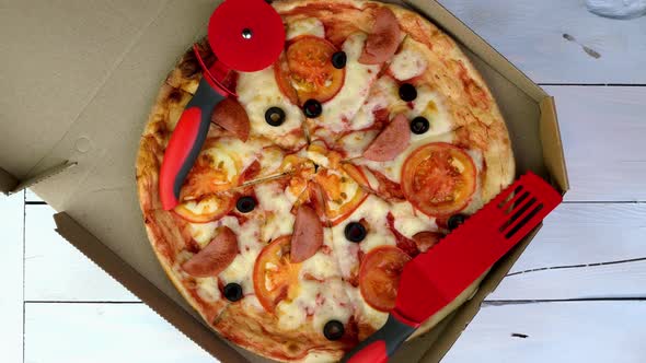 Fresh Round Pizza with Tomatoes Sausage Mozzarella and Olives in Cardboard Box Rotates Slowly