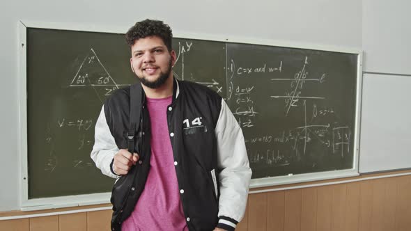 Portrait of Male Latin Student with Backpack at Blackboard