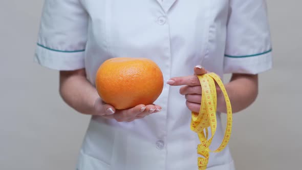 Nutritionist Doctor Healthy Lifestyle Concept - Holding Organic Grapefruit Fruit and Measuring Tape