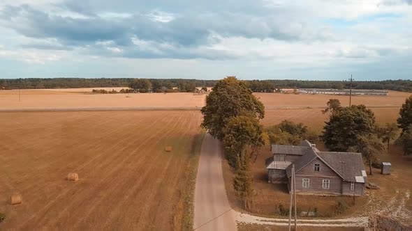 Flight Over Rural Road Among Ripe Cereal Fields Towards Farmhouses And Barns