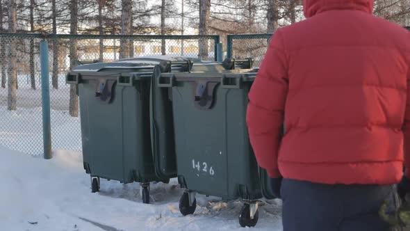 a Man in a Red Winter Jacket Throws a Christmas Tree Into a Trash Can After Celebrating New Year and