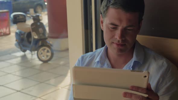 Man Working with Tablet PC in Cafe