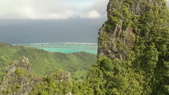 Aerial shot revealing the turquoise color sea of Mo'orea island behind a mountain peak