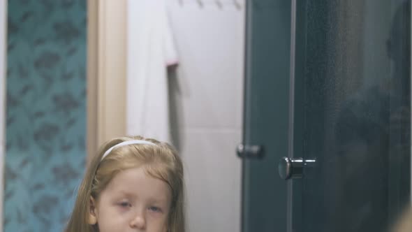 Girl with Blue Eyes Gargles Throat at Mirror in Bathroom