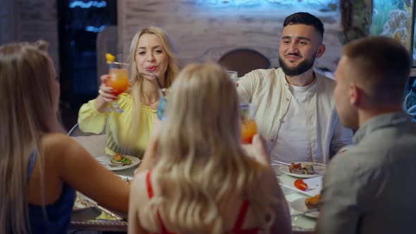 Happy Young Friends Toasting Clinking Glasses with Alcohol Drinking Cocktails and Whiskey in