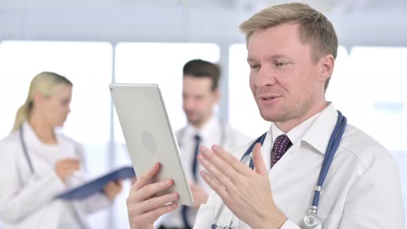 Portrait of Professional Male Doctor Doing Video Chat on Tablet