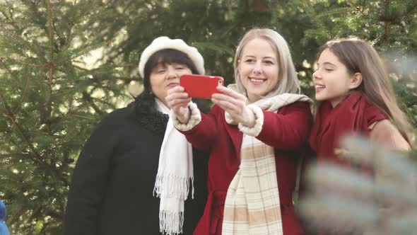 Mother with two daughters take a selfie near pine tree