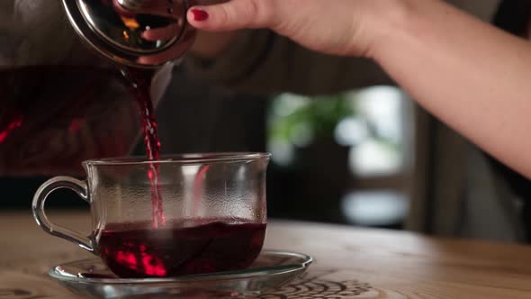 Woman Pouring Red Tea Into a Cup