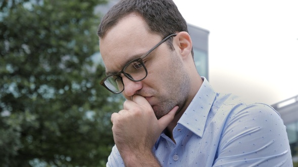 Attractive focused brown-haired man reading something on a laptop