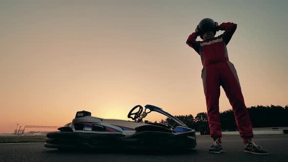 A Racer Puts on a Helmet While Standing Next to His Cart