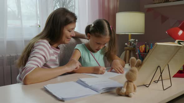 Mother And Daughter Doing Homework From School Together