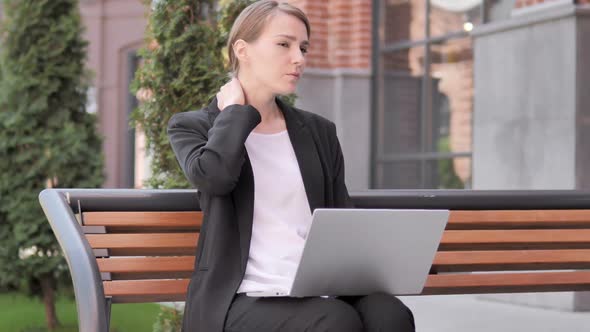 Young Businesswoman with Neck Pain Using Laptop Outdoor