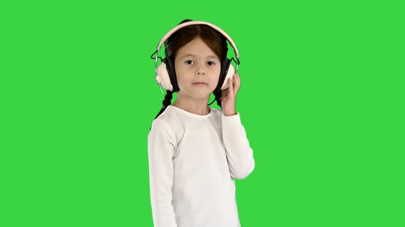 Little Girl Dressed in White Listening To the Music in Headphones and Nodding Her Head To the Rhythm