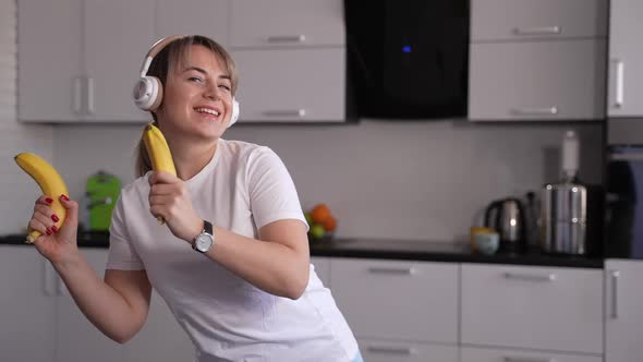 Happy Woman Dancing with Bananas in Home Kitchen