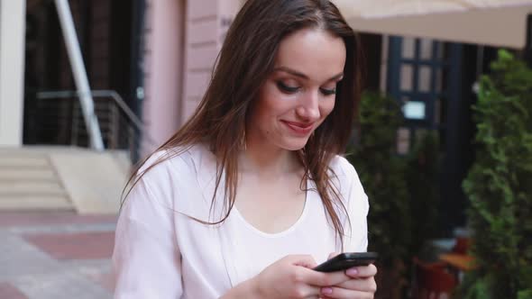 Woman using mobile phone on street near office building. 