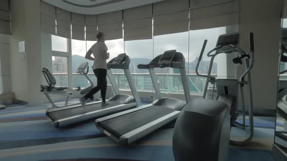 Woman working out on running machine and looking at city