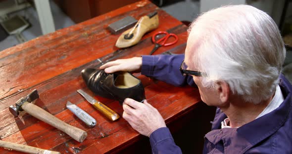 Shoemaker examining a shoe