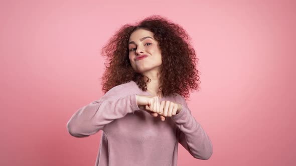 Beautiful Woman with Curly Hair Dancing with Head on Pink Studio Background