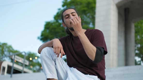 Closeup Portrait of Handsome Arab Man Sitting on Stairs and Smoking