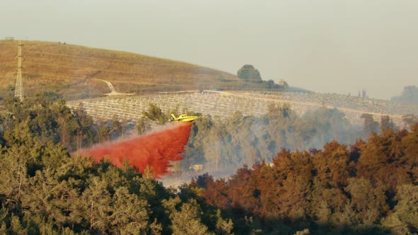 Fire fighter plane drops fire retardant on a forest fire in the hills