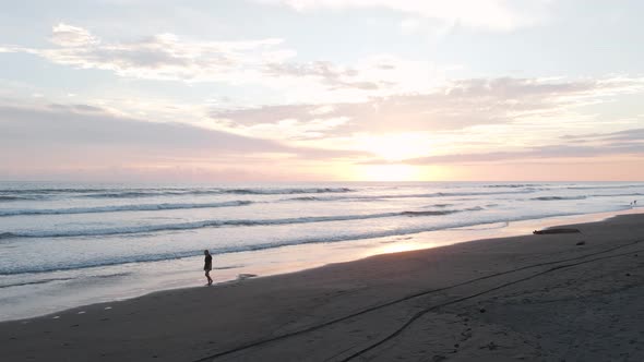 Woman walking along playa Bandera during a beautiful vibrant sunset in Puntarenas, Costa Rica. Panni