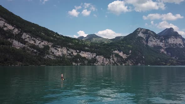 Drone, aerial flight to a stand up paddler on a yellow stand up paddle, sup, in the middle of a lake