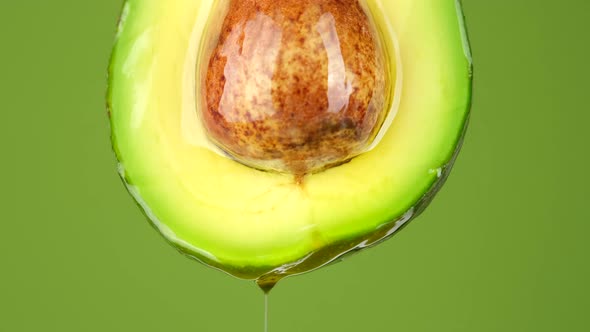 Half raw fresh organic green avocado fruit with oil stream