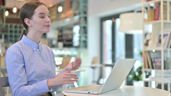 Video Chat on Laptop By Young Businesswoman in Cafe