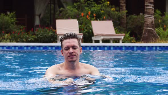 Young Handsome Caucasian Man Bathing and Relaxing in the Pool on a Sunny Day