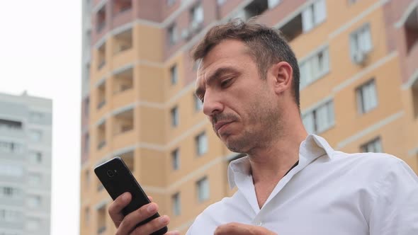 Serious Businessman in a White Shirt is Writing on the Phone Online