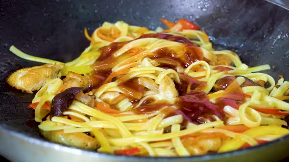 Pouring Red Sauce to Pasta with Vegetables on Frying pan and Tossing it