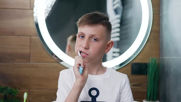 Happy Handsome Teenager with Blue Eyes which Cleaning His Teeth on the Camera alt