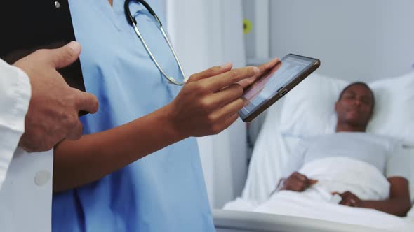 Close-up of multi-ethnic doctors discussing x-ray report on digital tablet in ward at hospital