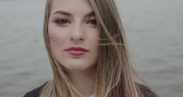 Beautiful Girl with Blowing Hair Looking Into Camera and Smiling Lightly