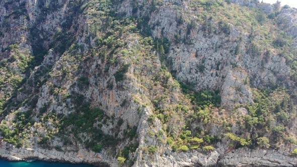 aerial drone circling large green mountain cliffs around Butterfly Valley in Fethiye Turkey on a sun