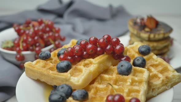Spinning Belgian Waffles Garnished with Berries and Soaked in Maple Syrup